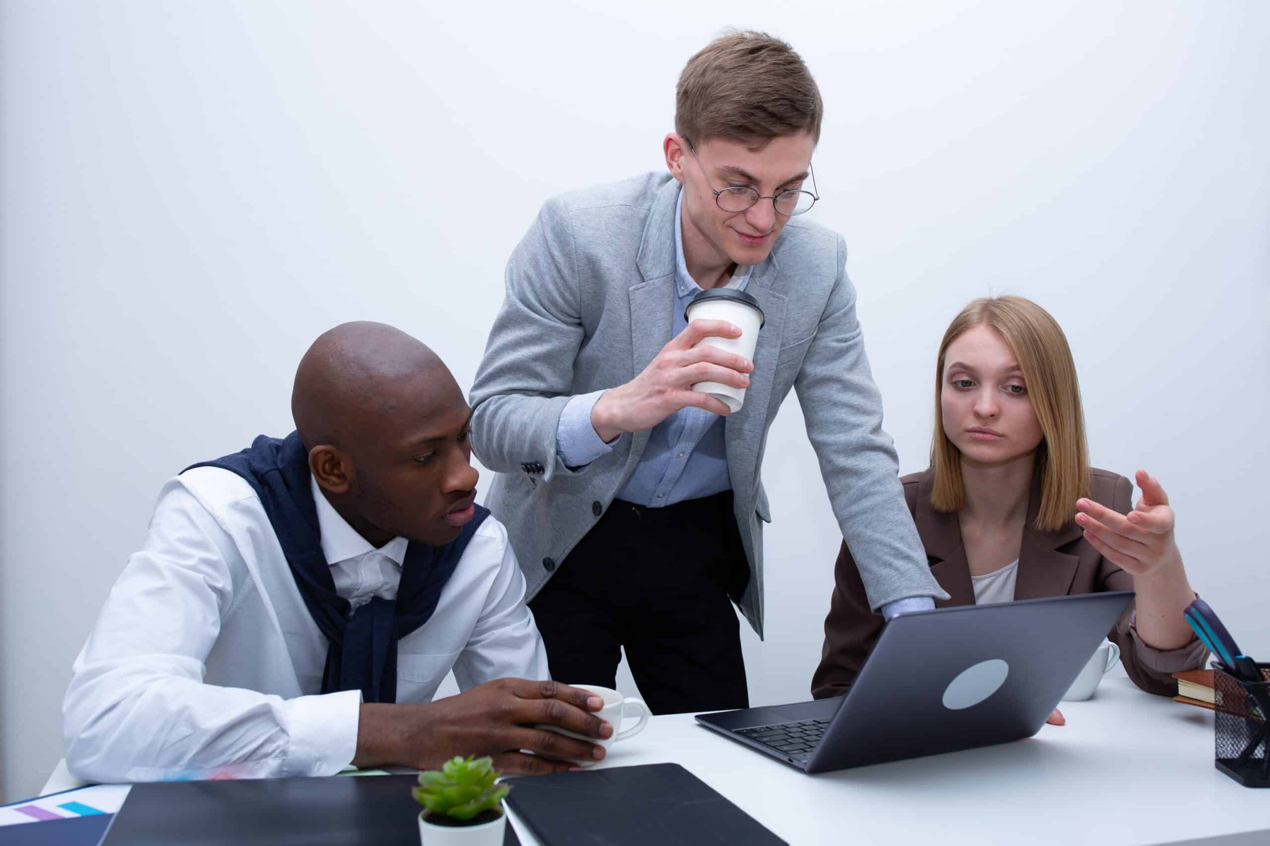 Three business people looking at a laptop in an office.